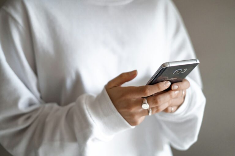 Moving from panic purchases to planned repayments starts with your statements: a person in a white jumper checking their household budget on a mobile phone